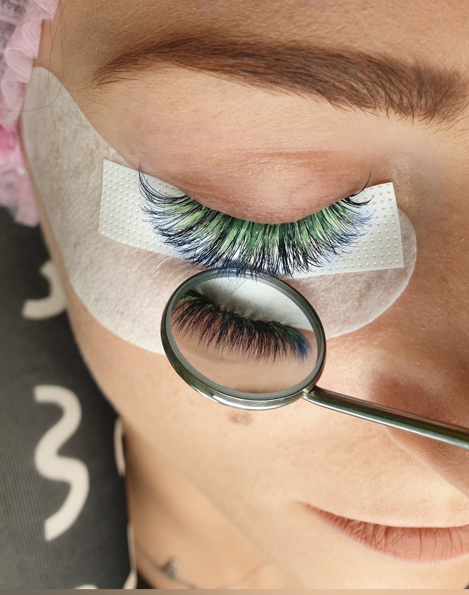 Wimperset in groen en blauw, bekeken in een handspiegel